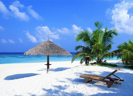 Une plage tropicale, avec transat en bois et parasol en paille.
